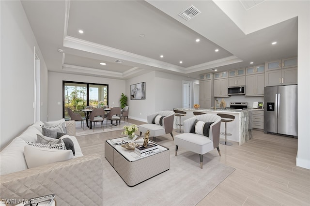 living room with crown molding, sink, and a tray ceiling