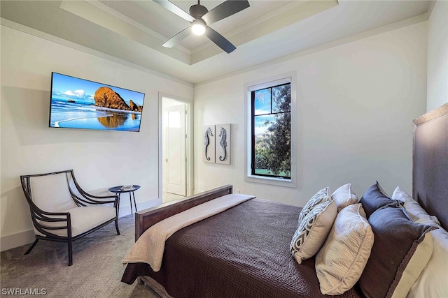 carpeted bedroom with a raised ceiling and ceiling fan