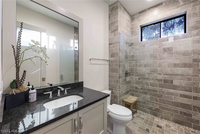 bathroom featuring a tile shower, toilet, and a wealth of natural light