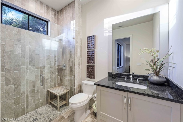 bathroom with tile floors, toilet, large vanity, and walk in shower