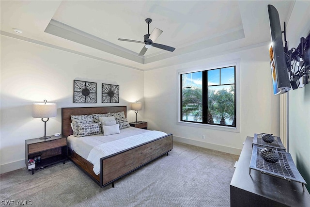 carpeted bedroom with ceiling fan and a tray ceiling