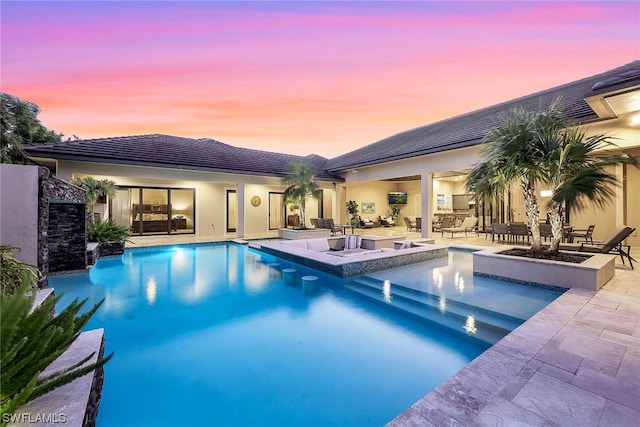 pool at dusk featuring a patio