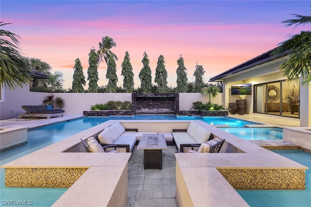 pool at dusk with an outdoor hangout area and a patio area