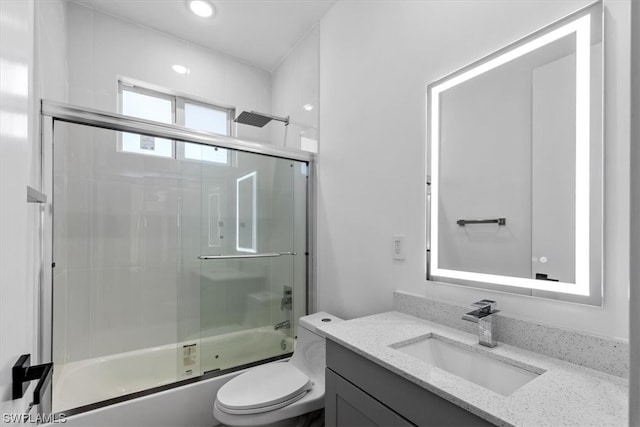 full bathroom featuring toilet, vanity, and bath / shower combo with glass door