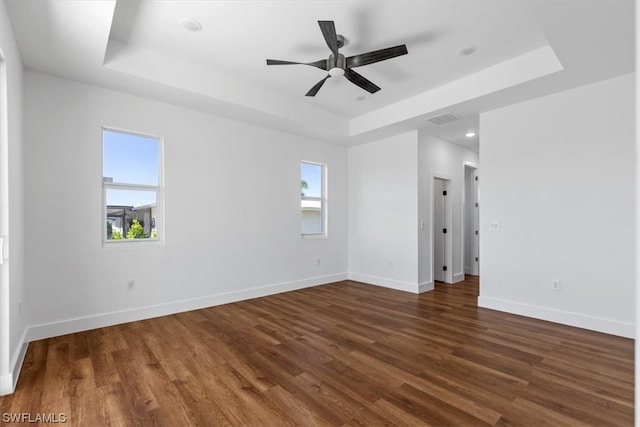 spare room featuring dark wood-type flooring, a tray ceiling, and ceiling fan