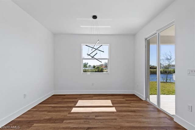 empty room featuring a water view and dark hardwood / wood-style flooring