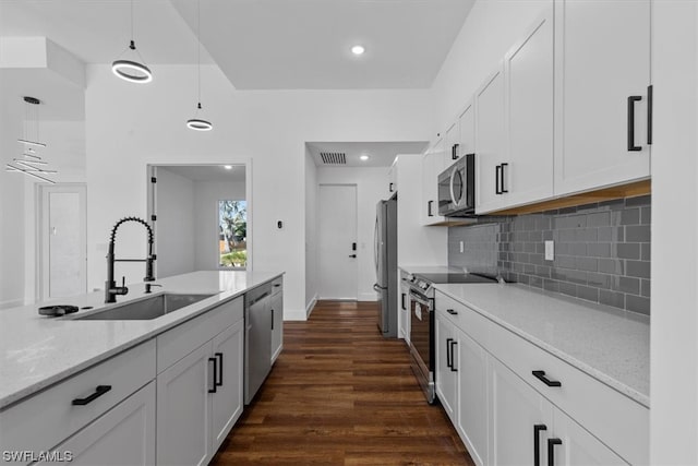 kitchen with stainless steel appliances, decorative light fixtures, tasteful backsplash, white cabinetry, and dark hardwood / wood-style flooring