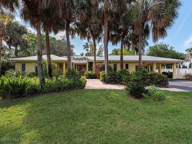 single story home with metal roof, a front lawn, an attached carport, and stucco siding