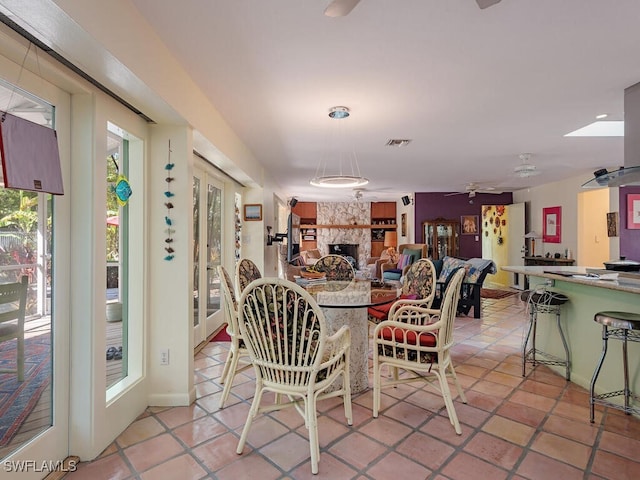 dining room with a large fireplace, light tile patterned flooring, and visible vents