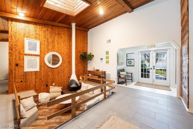 interior space with french doors, beamed ceiling, wood ceiling, wooden walls, and a skylight