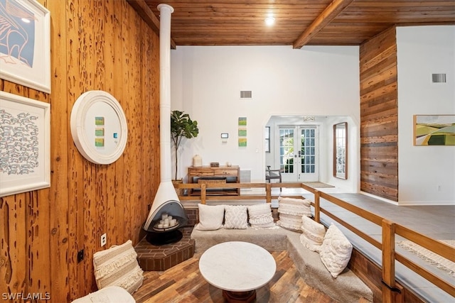 interior space featuring beam ceiling, a wood stove, wood walls, hardwood / wood-style flooring, and wooden ceiling