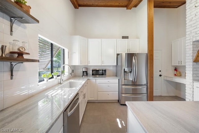 kitchen with beamed ceiling, white cabinets, backsplash, and appliances with stainless steel finishes