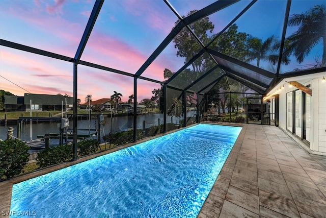 pool at dusk featuring a boat dock, a lanai, a patio area, and a water view