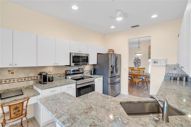 kitchen featuring tasteful backsplash, white cabinetry, appliances with stainless steel finishes, and kitchen peninsula