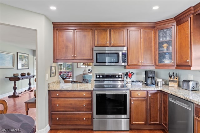 kitchen featuring light stone counters, hardwood / wood-style flooring, and stainless steel appliances