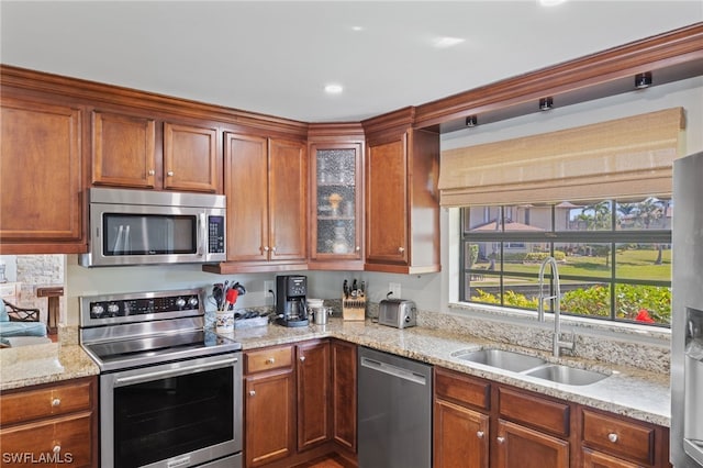 kitchen with light stone counters, stainless steel appliances, and sink