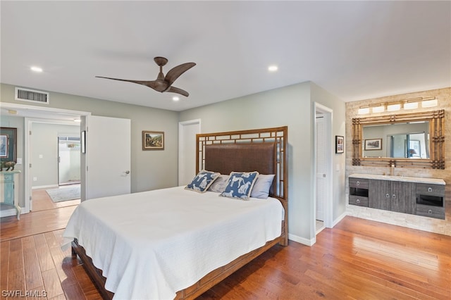 bedroom featuring a closet, ensuite bath, ceiling fan, and hardwood / wood-style flooring