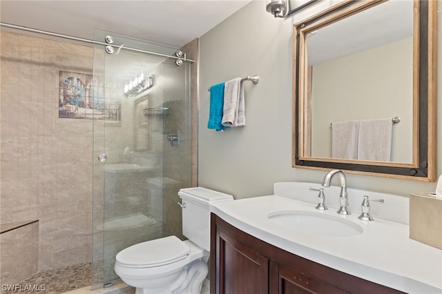 bathroom featuring vanity, a shower with shower door, and toilet