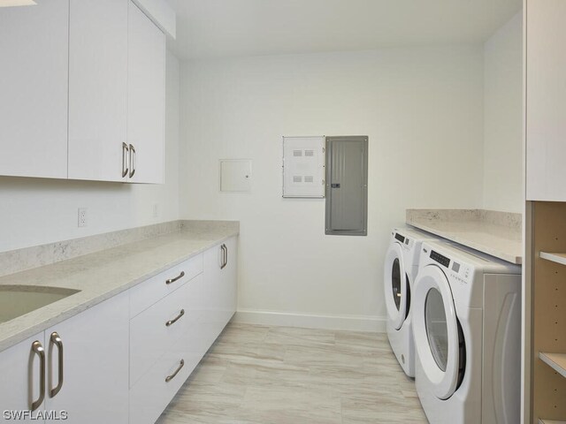 laundry room featuring cabinets, sink, electric panel, and washer and clothes dryer