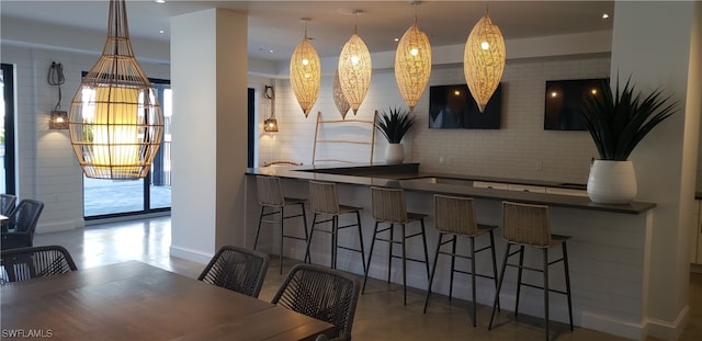 bar featuring pendant lighting and concrete flooring