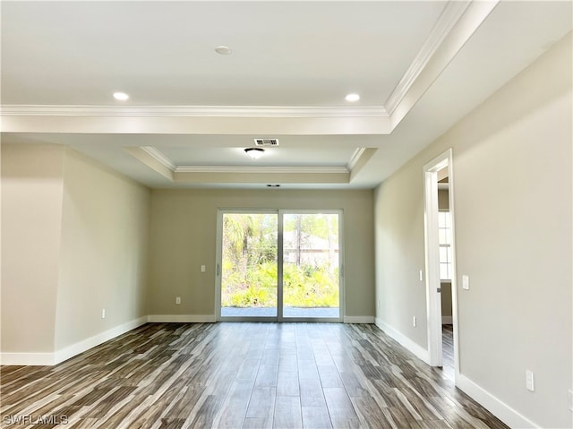 empty room featuring dark wood-type flooring, ornamental molding, and a tray ceiling