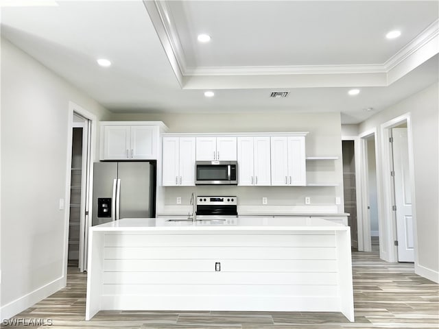 kitchen featuring appliances with stainless steel finishes, white cabinetry, a raised ceiling, and light wood-type flooring