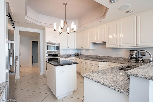 kitchen featuring a kitchen island, a chandelier, a raised ceiling, and stainless steel appliances