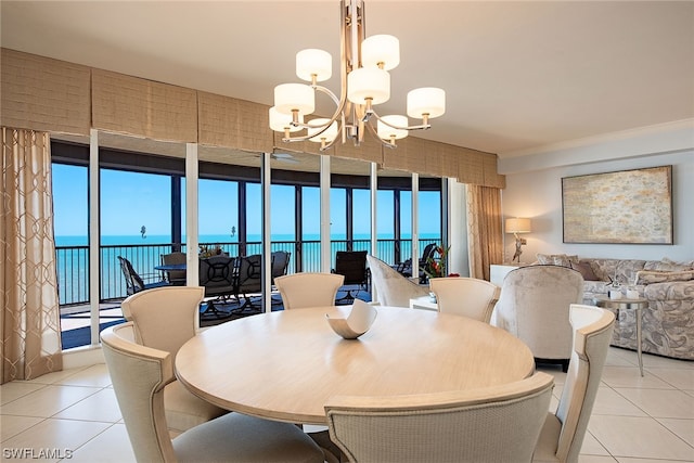 tiled dining space featuring a water view, a notable chandelier, and a wall of windows