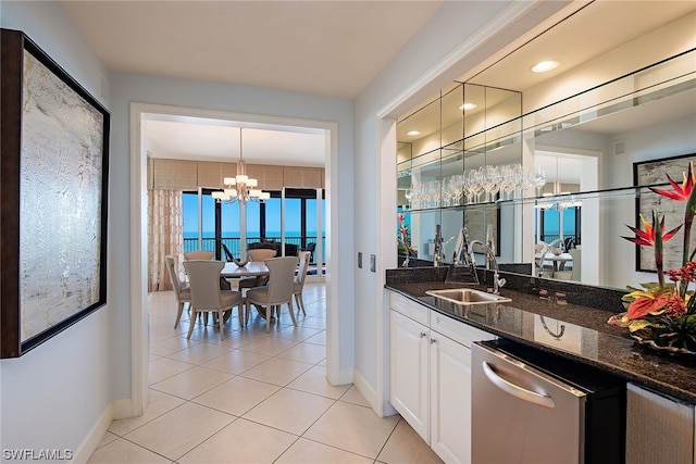 bar featuring sink, dark stone countertops, white cabinets, dishwasher, and a notable chandelier