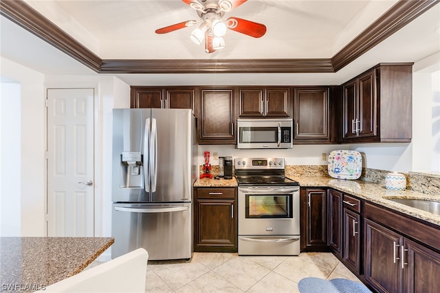 kitchen with ceiling fan, appliances with stainless steel finishes, light tile floors, light stone counters, and dark brown cabinets