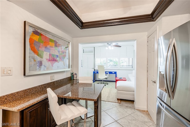 dining area with light tile flooring, a tray ceiling, and ceiling fan