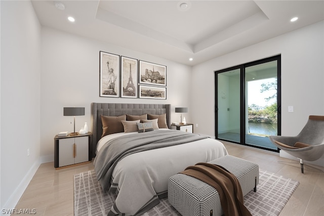 bedroom with light hardwood / wood-style flooring, access to exterior, and a tray ceiling