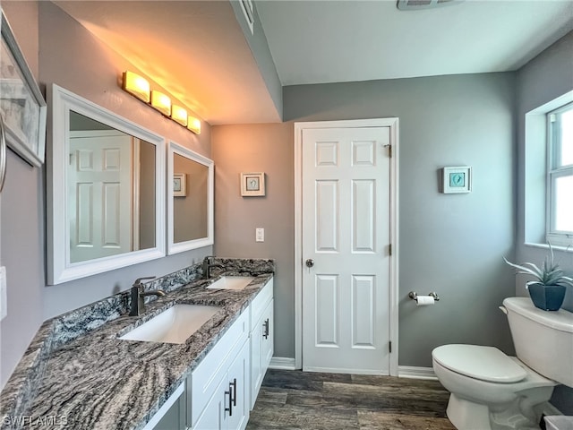 bathroom with double sink vanity, toilet, and hardwood / wood-style flooring