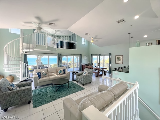 living room featuring light tile flooring, a water view, ceiling fan, and a towering ceiling