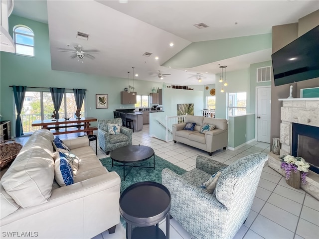 tiled living room featuring high vaulted ceiling, a fireplace, and ceiling fan