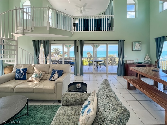 tiled living room with a healthy amount of sunlight, ceiling fan, and a towering ceiling