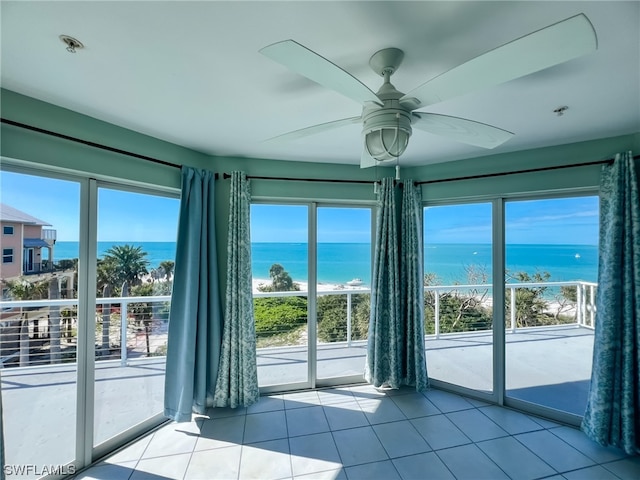 tiled spare room with a water view and ceiling fan