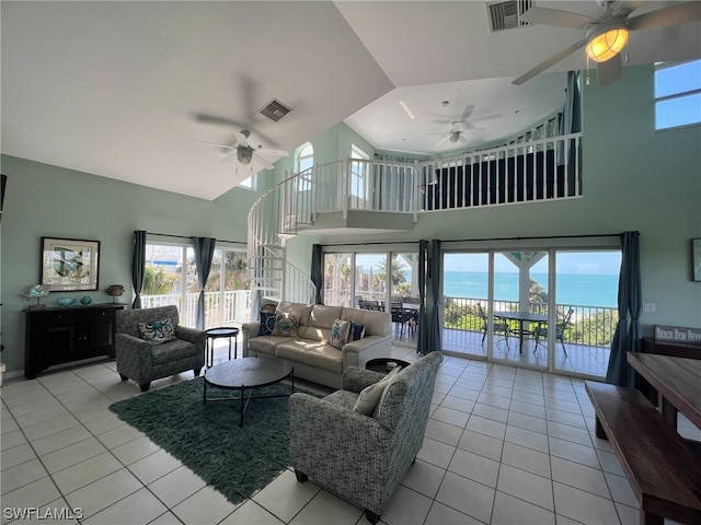 living room with a water view, ceiling fan, light tile floors, and a high ceiling