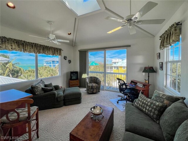 living room with carpet flooring, vaulted ceiling with skylight, and ceiling fan