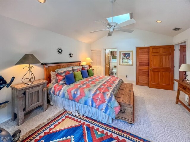 carpeted bedroom with vaulted ceiling, ensuite bath, and ceiling fan