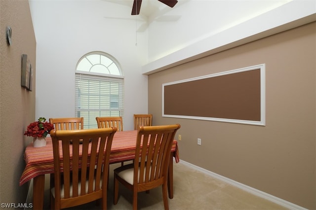 dining space with ceiling fan, vaulted ceiling, and light colored carpet