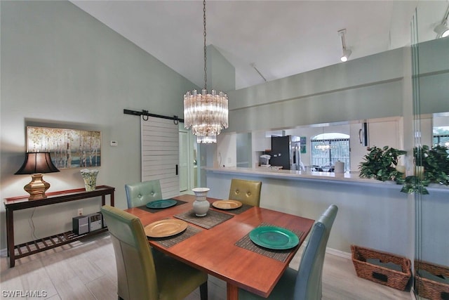 dining area featuring a barn door, light hardwood / wood-style flooring, high vaulted ceiling, and a notable chandelier