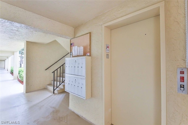 hall featuring elevator, concrete floors, and a mail area