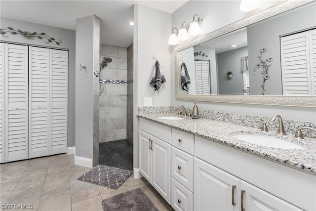 bathroom with a tile shower, double sink, tile floors, and large vanity