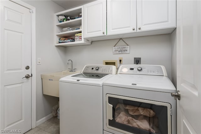 clothes washing area featuring cabinets, washing machine and clothes dryer, electric dryer hookup, sink, and light tile floors