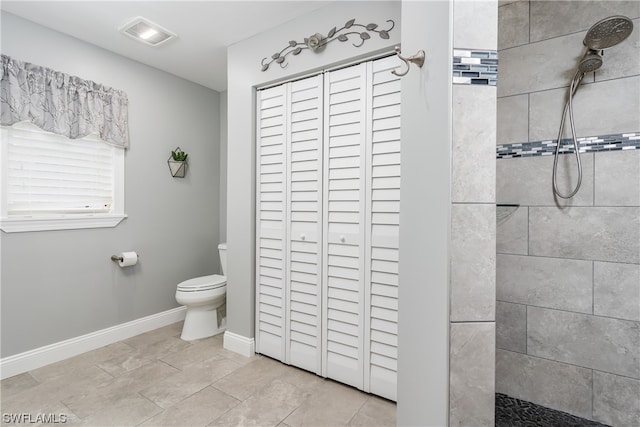 bathroom with a tile shower, tile flooring, and toilet