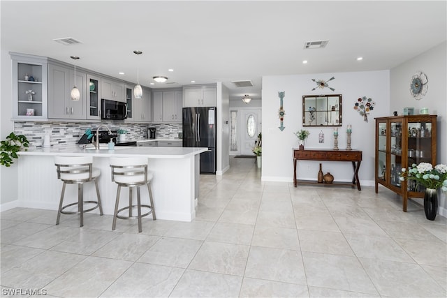 kitchen featuring backsplash, appliances with stainless steel finishes, light tile flooring, and kitchen peninsula