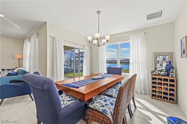 dining space with an inviting chandelier, a wealth of natural light, light tile flooring, and a water view