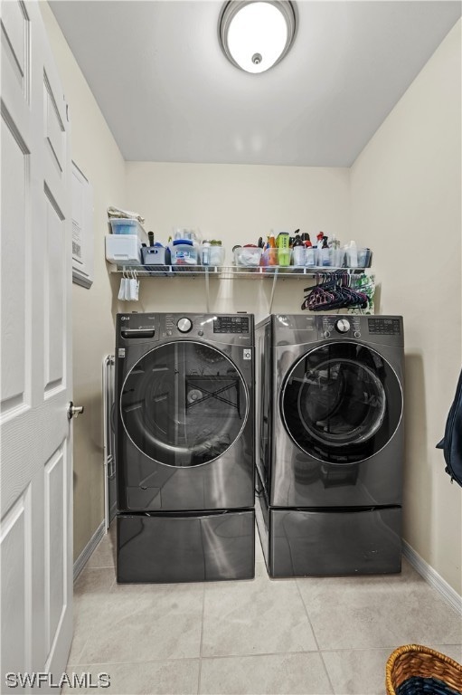 laundry area with light tile floors and washer and clothes dryer