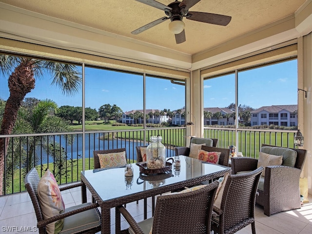 sunroom with ceiling fan and a water view